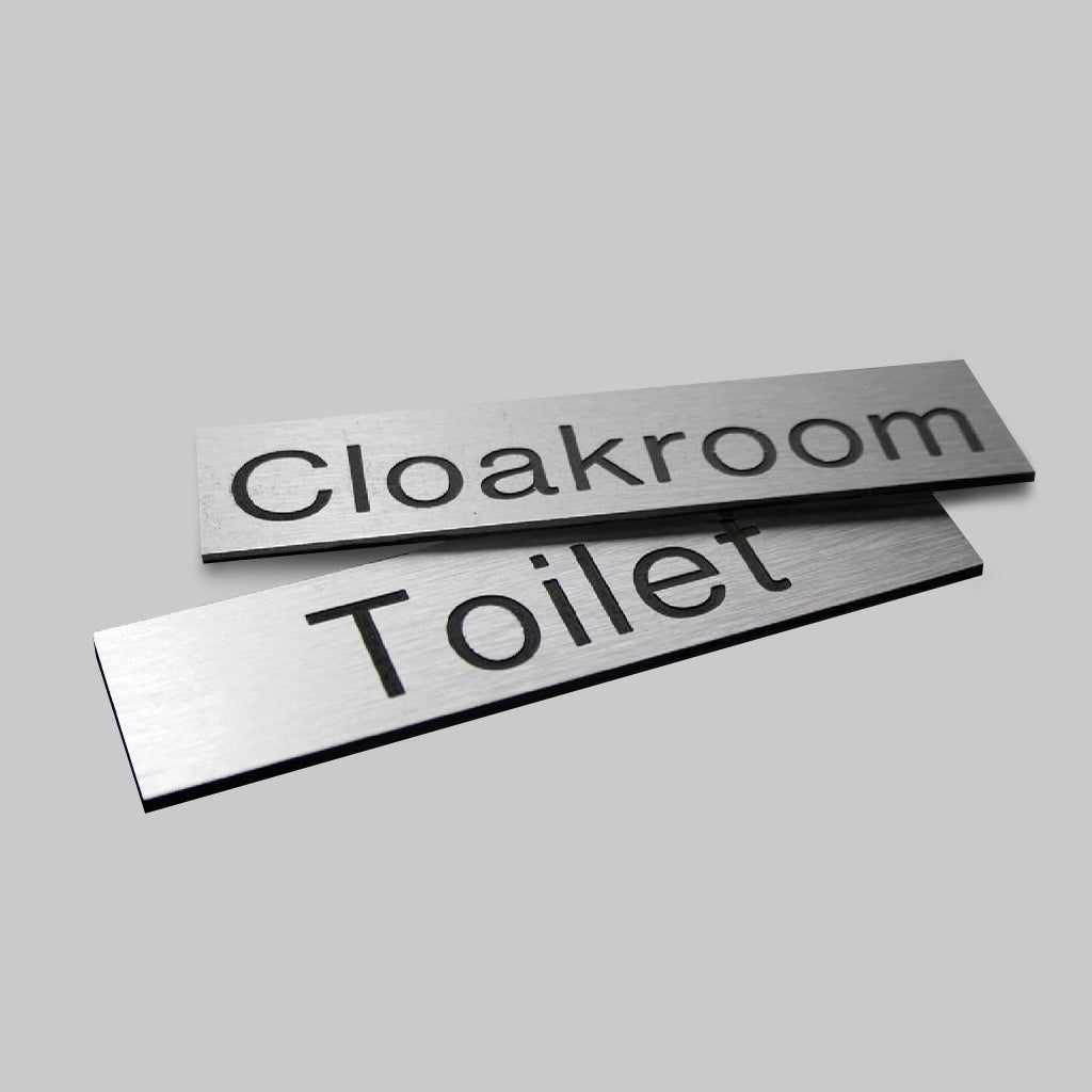 Engraved Sign With Adhesive Backing - 140 x 35mm Dia Black Text On Aluminium Effect - Ready Set SuppliedEngraved Sign With Adhesive Backing - 140 x 35mm Dia Black Text On Aluminium Effect51496
