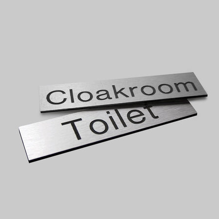 Engraved Sign With Adhesive Backing - 140 x 35mm Dia Black Text On Aluminium Effect - Ready Set SuppliedEngraved Sign With Adhesive Backing - 140 x 35mm Dia Black Text On Aluminium Effect51496